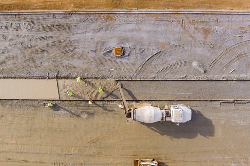 At construction site concrete mix truck is workers pouring cement during construction of sidewalk